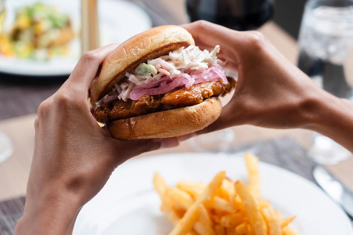 Bistro-933– Sandwich with French Fries Hands hold a grilled sandwich with slaw and pickled onions at Bistro 933 in South Bend, IN